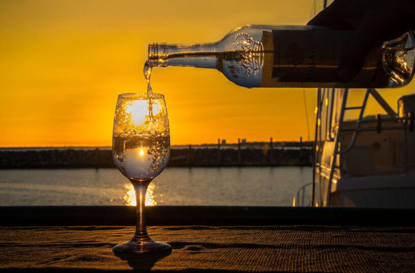 Glass of champagne being poured during sunset at the waterfront.